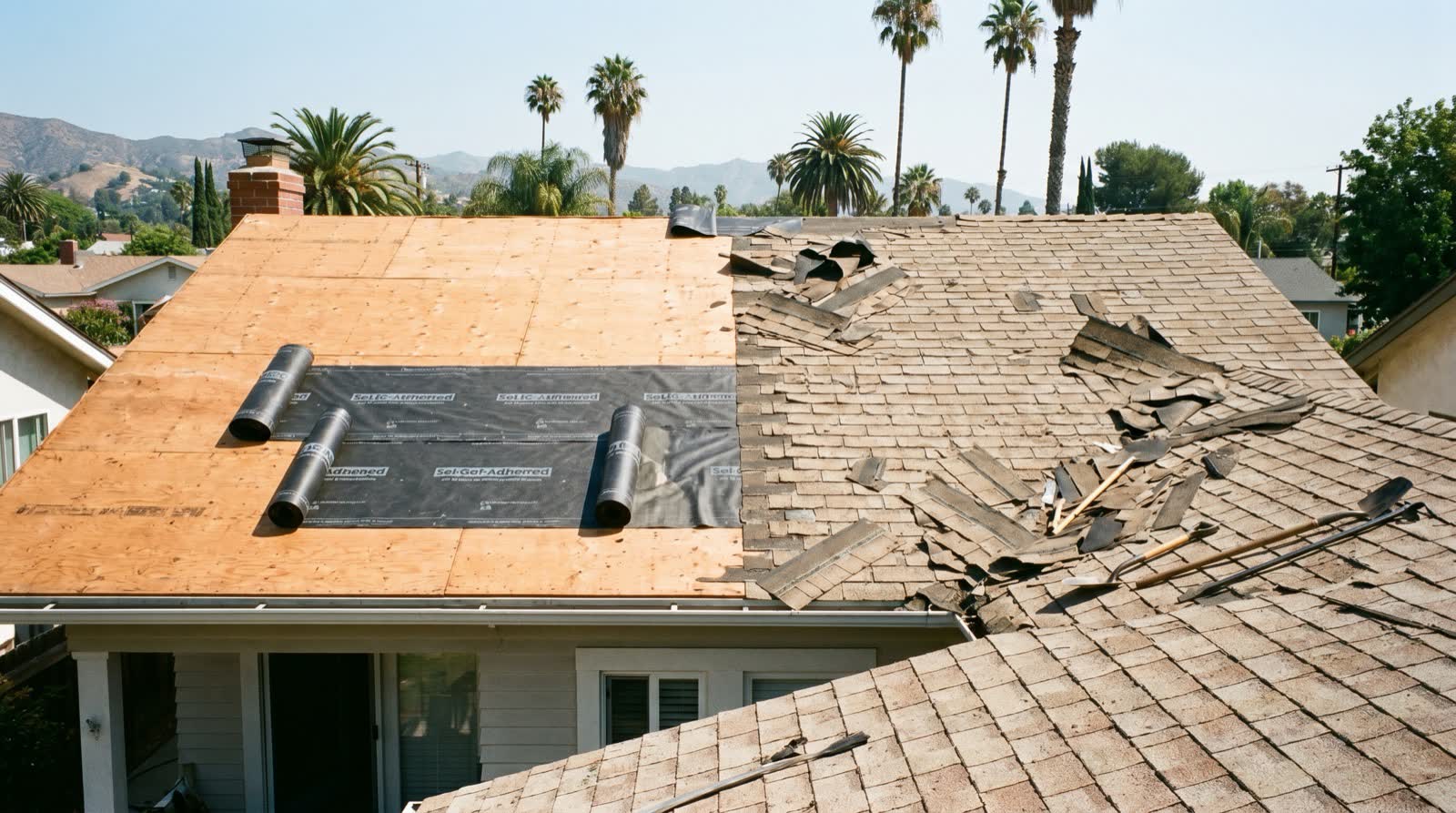 A roof mid tear-off with old shingles stripped down to the deck